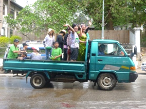 ピックアップトラックの荷台から水をかける若者たち