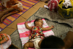 他に行き場もなく、暑さと湿度の中で眠る被災者の子ども