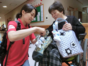 車いすの女性にバッグを渡す難民を助ける会の宮本奈穂子