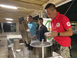 大きな釜からご飯をよそい、炊き出しを行うAARスタッフ