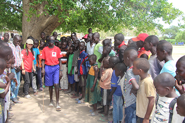 目隠しをして杖をつきながら歩いている