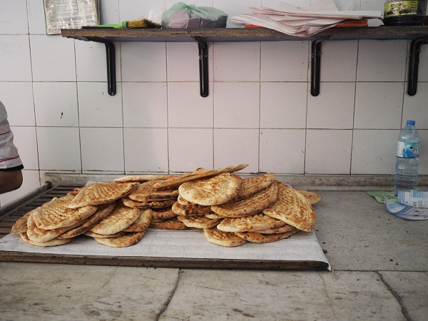 "カウンターに無造作に重ねられたパン、20枚くらいある。