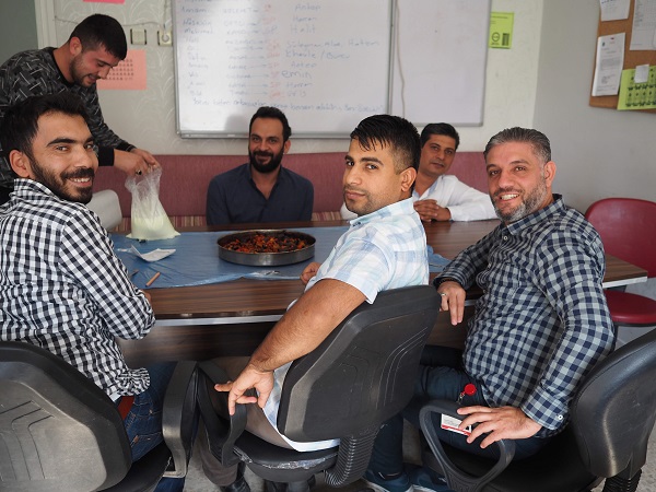 四角いテーブルを囲んで座っている男性6人