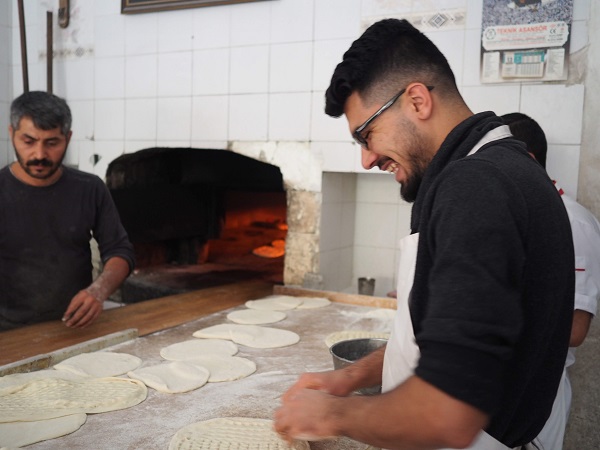 パン屋で働く男性、模様付けする男性とカウンターの向こう側、オーブン近くに焼き担当の男性。