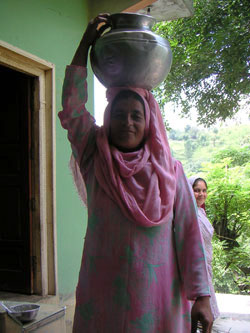 給水システムの復旧が待ち望まれています 水の入ったつぼを頭の上に乗せた女性