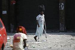 両手が使えないので頭に荷物を載せて運ぶ被災者 両手が使えないので頭に荷物を載せて運ぶ松葉杖の被災者