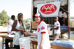 被災者の女性に支援物資を手渡す堀越芳乃(右)