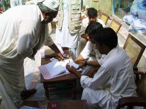 クーポン券を見せ、帳簿にサイン(拇印)をしてから物資を受け取ります 配付対象者の帳簿にサイン(拇印)をする男性