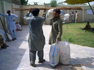 左の男性が持っている棒は蚊帳の支柱です 支援物資を持ち帰る男性