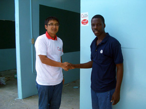 仮校舎完成を祝って 握手を交わすサドニ牧師と大西清人(左)