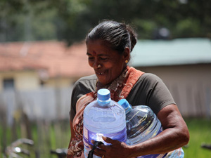 支援物資の飲料水を受け取る女性