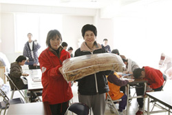 陸中海岸青少年の家の被災者に毛布を届ける難民を助ける会ボランティアスタッフ（左）