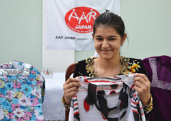 服を手に笑顔を見せるショフゾダさん