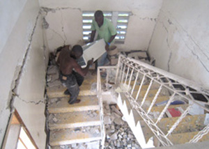 崩れかけた階段を通って備品を運びだす