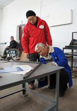 車いすの部品を確認するラフモノフさんと南専門家