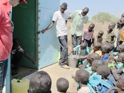 トイレの使い方を説明する先生と話を聞く子どもたち