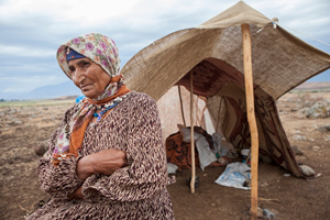 簡素なテントの前にたたずむ中年の女性
