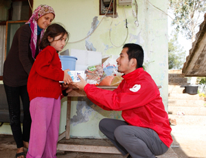 支援物資の牛乳を受け取る女の子と東京事務局の景平義文