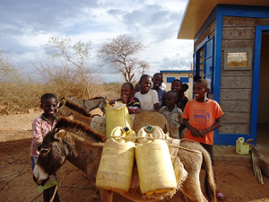 ポリタンクを担いだロバと子どもたち