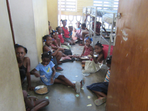 床に座って食事する子どもたち