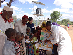 給水設備の使い方に関するパンフレットをのぞきこむ人々