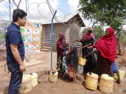 給水設備の前で話す現地の女性と高城