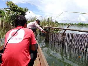 舟に乗って水浸しになった村をいくAAR職員