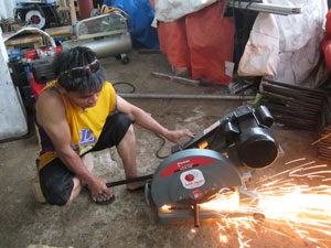 切断機で鉄パイプを切る。火花が上がる