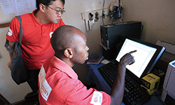 パソコンの画面を指さす現地スタッフと駐在員