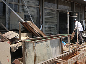 家屋から廃棄物などを取り出す男性