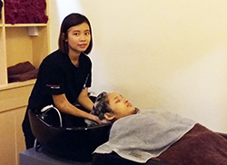 きれいな内装のサロンで、ニン・ニン・イさんがお客さんにシャンプーをしている様子