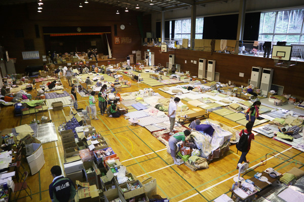 小学校の体育館は避難者の布団が並べてあり、そばには支援物資が山積みになっている