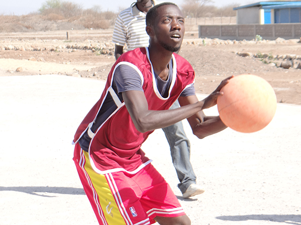 バスケットボールを手にする選手、後ろに審判がいる