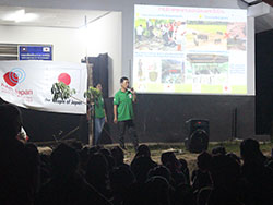 スクリーンに衛生環境に関する映像を映し、マイクを持ち村人に伝える