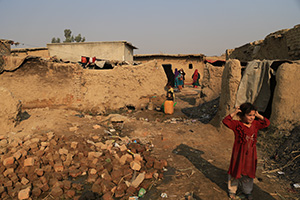 土やレンガが雑多に積まれたアフガニスタン難民居住地。女の子が立っている