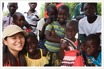 AAR職員と、ウガンダの子どもたち10人近くが笑顔でこちらを向いている